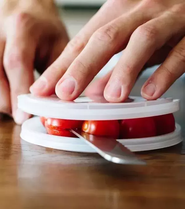 1: Slice your baby tomatoes using old plastic lids. It's super easy, quick, and it works well!